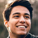 A young man smiling outdoors.