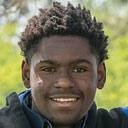 A young man wearing a blue jacket and black shirt.