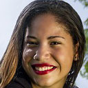 A woman with long hair and red lipstick smiling.